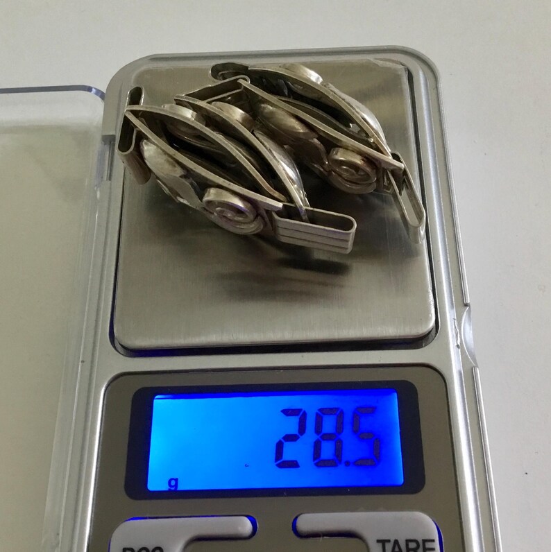 May include: A silver watch band with multiple links is on a digital scale that reads 28.5 grams.