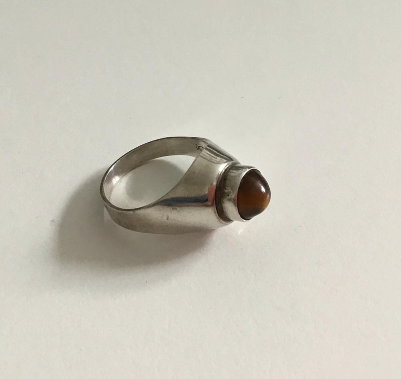 May include: A silver ring with a brown tiger's eye stone.