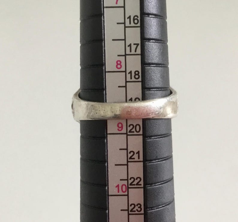 May include: A silver ring with a textured band, measured against a ruler with markings from 16 to 23.