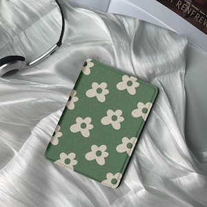 May include: A green and white floral patterned e-reader cover. The cover is made of a soft, textured fabric.