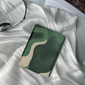 May include: A green and beige e-reader with a wavy abstract pattern on the cover.