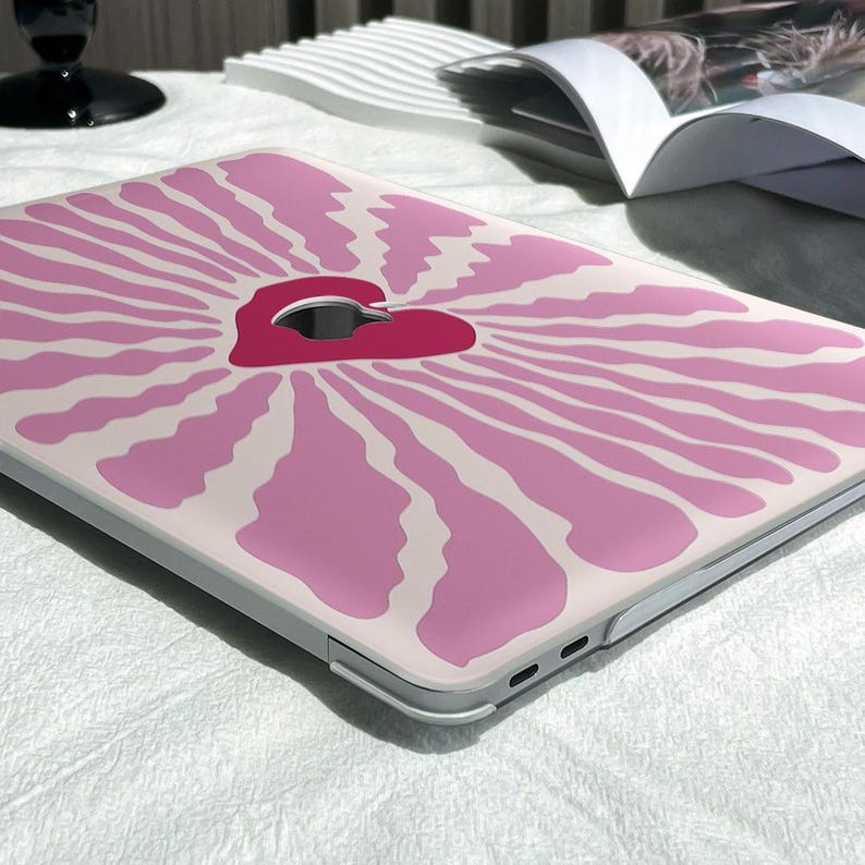 May include: A pink and white laptop skin with a pink heart design. The heart has a white outline and is in the center of the design.