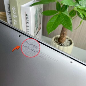 May include: Close-up of the bottom of a silver laptop with the text "Designed by Apple in California Assembled in China Model A2337" printed on the back.