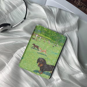 Könnte beinhalten: Ein grüner und brauner illustrierter Buchumschlag mit einem Dackel in einem Park mit anderen Hunden und Menschen. Der Buchumschlag hat einen schwarzen Rand.