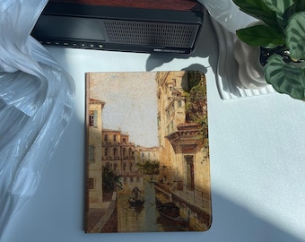 May include: A vintage-style notebook cover featuring a watercolor painting of a canal in Venice, Italy. The painting depicts buildings lining the canal, with a gondola in the water.