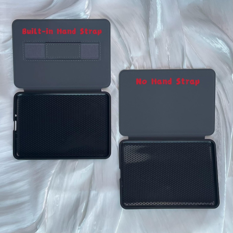 May include: Two open, gray tablet cases. The case on the left has a built-in hand strap, while the case on the right does not. Both cases have a black, textured interior. The text "Built-in Hand Strap" and "No Hand Strap" are visible.