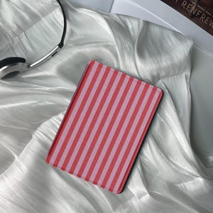 May include: A red and white striped e-reader cover. The cover is made of a soft, textured material.
