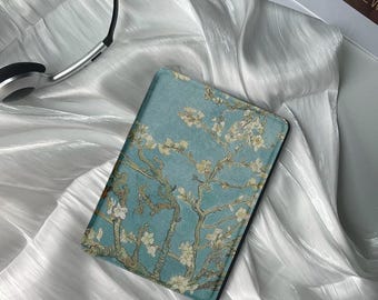 May include: A blue and white e-reader cover with a painting of a blooming almond tree branch. The cover is made of a soft, durable material and has a sleek, modern design.