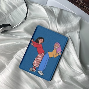 May include: A blue tablet case featuring a cartoon illustration of two people. One person is wearing a red sweater and a red and white checkered skirt, and the other is wearing a yellow shirt and blue pants. The case is on a white, silky surface.