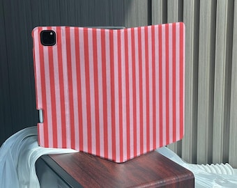 May include: A tablet case featuring a vertical striped pattern in alternating shades of red and light pink. The case includes a cutout for a camera lens on the top left corner and a side slot designed to hold a stylus pen securely in place.