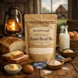 May include: A rustic still life featuring a bag of "Decemberstuff Old Fashioned Amish Bread Mix" with a loaf of bread, butter, milk, and eggs. The scene is set on a wooden table with a lit lantern in the background.