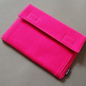 May include: A vibrant pink rectangular clutch bag with a flap closure. The bag is made of a textured fabric and has two rectangular accents on the flap. The brand name "jijiu" is printed on a small tag.