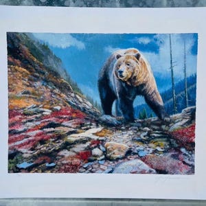Puede incluir: Una pintura detallada de un oso pardo caminando sobre una ladera rocosa. El oso tiene pelaje marrón y se encuentra en un paisaje montañoso con follaje rojo y verde, cielo azul y árboles de hoja perenne.