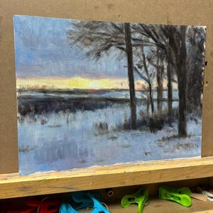 Puede incluir: Una pintura al óleo sobre lienzo que representa un paisaje invernal al atardecer. La escena muestra árboles oscuros en silueta a la derecha contra un cielo azul pálido con un horizonte de tonos amarillos y naranjas. El suelo está cubierto de nieve.