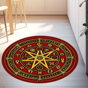 Puede incluir: Una alfombra redonda roja con un pentagrama dorado y símbolos astrológicos. La alfombra tiene un borde negro y está rodeada de un fondo blanco.