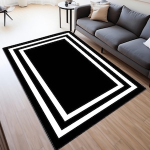 May include: Black and white area rug with a double white border. The rug has a modern geometric design.
