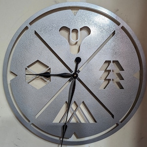 May include: A silver metal clock with a black clock hand and four symbols. The symbols are a stylized 'X', a stylized 'Destiny' logo, a stylized 'Hunter' logo, and a stylized 'Warlock' logo.