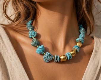 May include: A necklace featuring irregular, tumbled turquoise stones interspersed with smooth, polished gold-toned beads. The turquoise stones display natural dark veining, while the gold beads vary in shape, creating a textured, multi-material design that rests around the neck.
