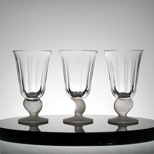 May include: Three clear glass drinking glasses with a frosted finish on the base and stem. The glasses have a fluted design and a rounded bowl.