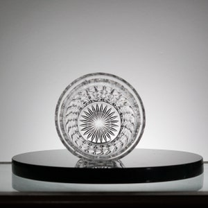 May include: A clear glass tumbler with a cut-glass design. The glass has a starburst pattern at the bottom.