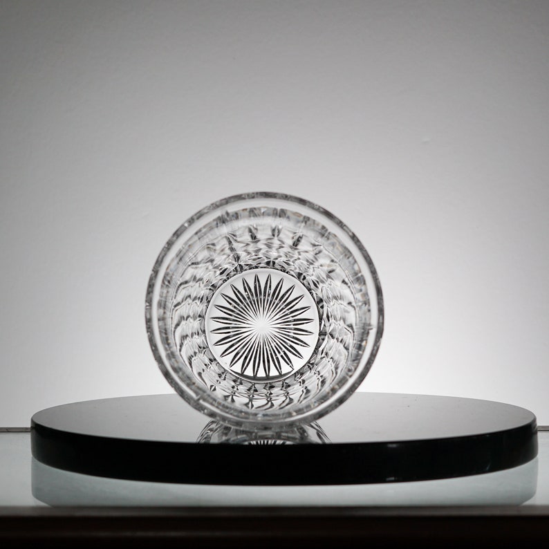 May include: A clear glass tumbler with a cut-glass design. The glass has a starburst pattern at the bottom.