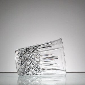 May include: A clear glass tumbler with a diamond-shaped pattern. The glass is empty and tilted to the side.