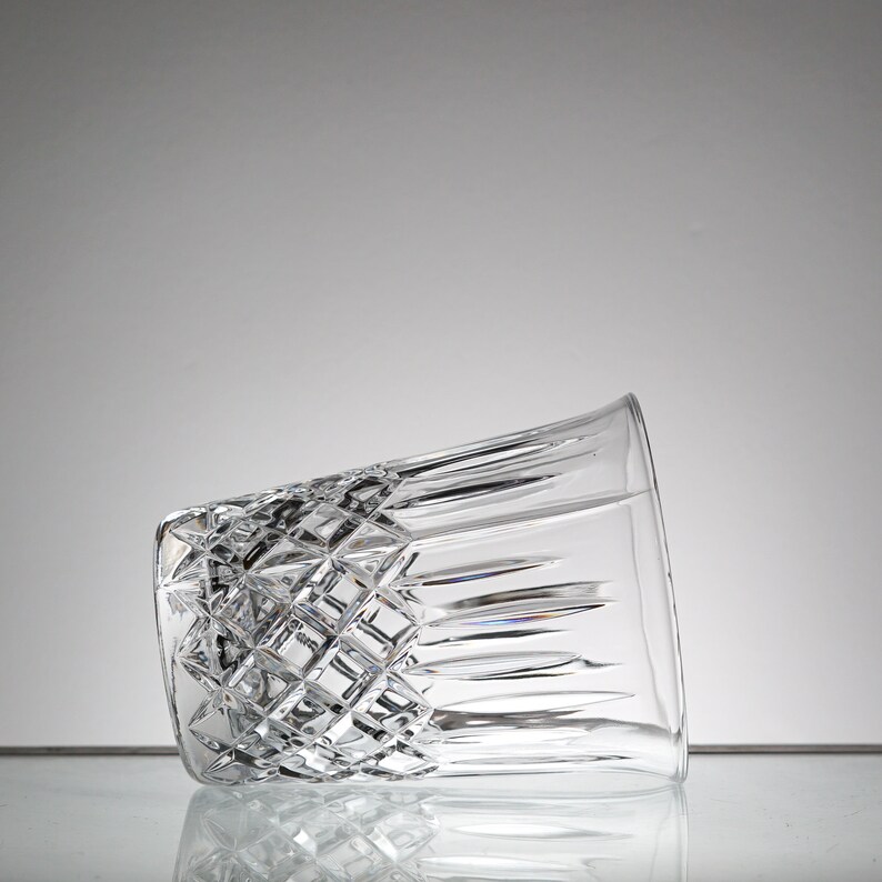 May include: A clear glass tumbler with a diamond-shaped pattern. The glass is empty and tilted to the side.