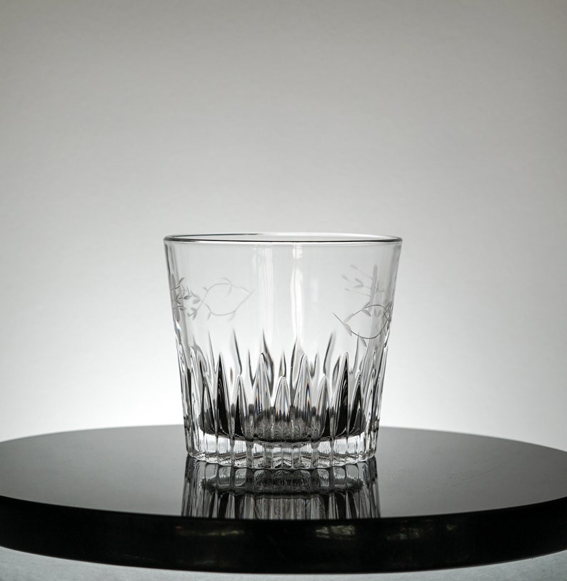 Puede incluir: Un vaso de vidrio transparente con un dise&ntilde;o de vidrio cortado. El vaso tiene una base ancha y un lado recto.