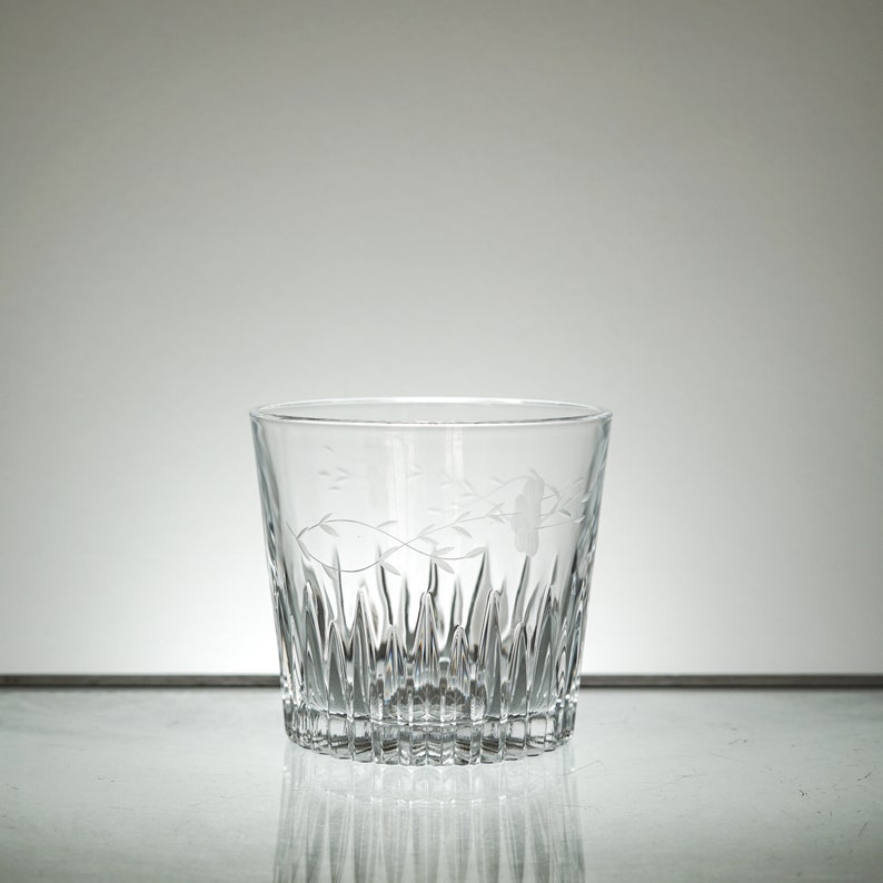 Puede incluir: Un vaso de vidrio transparente con un dise&ntilde;o de vidrio cortado y un patr&oacute;n floral grabado.