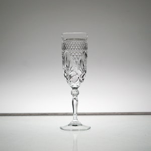 K&ouml;nnte beinhalten: Eine klare Champagnerfl&ouml;te aus Glas mit geschliffenem Kristallmuster. Die Fl&ouml;te hat einen hohen, schlanken Stiel und eine breite, schalenf&ouml;rmige Oberseite.