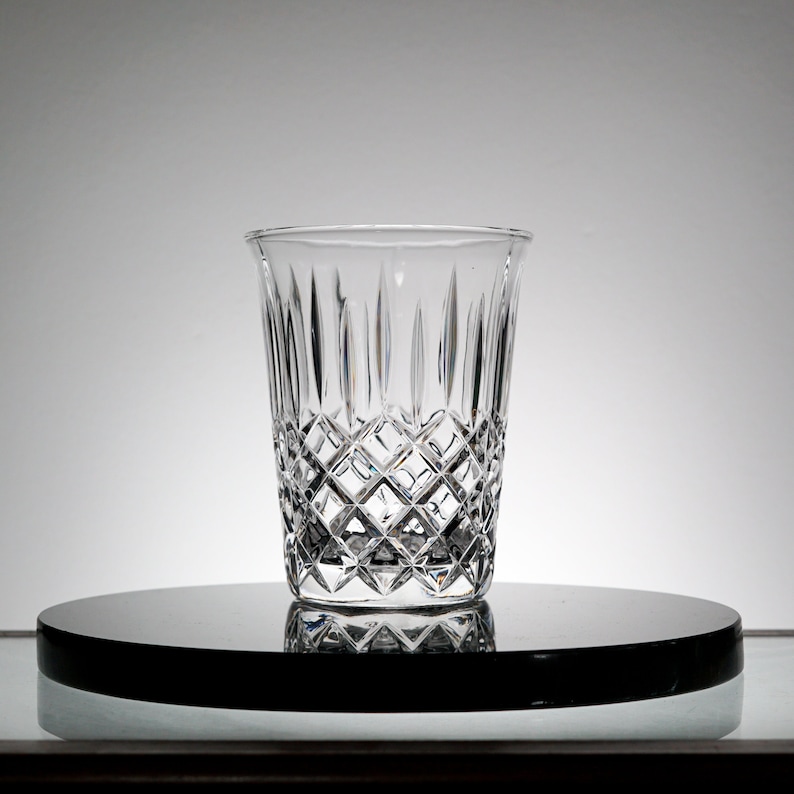 May include: A clear glass with a diamond pattern. The glass is sitting on a black circular surface.
