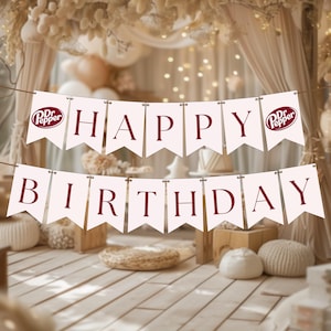May include: A banner with the words "HAPPY BIRTHDAY" in burgundy letters. The banner is strung across a room decorated with neutral tones, including beige curtains and wooden boxes. The Dr. Pepper logo is on the banner.