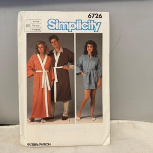 Könnte beinhalten: Simplicity-Schnittmusterumschlag mit Abbildungen von Bademänteln. Der Umschlag hat die Nummer 6726 oben. Die Bademäntel sind in Orange-, Braun- und Blautönen mit weißen Akzenten gehalten. Die Worte "PATTERN/PATRON" stehen unten.