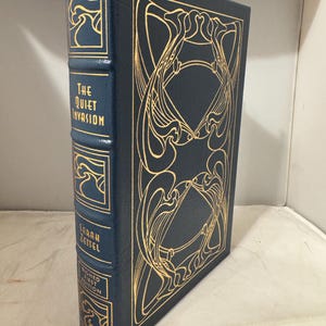 May include: A dark blue hardcover book titled "The Quiet Invasion" by Sarah Zettel. The cover and spine feature gold Art Nouveau designs and lettering. The book is a signed first edition.