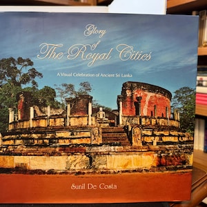 May include: A book titled "Glory of The Royal Cities" with a visual celebration of ancient Sri Lanka. The cover features a detailed image of ancient architecture with a blue sky background. The author's name, Sunil De Costa, is at the bottom.