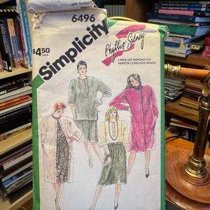 May include: A Simplicity 6496 sewing pattern envelope featuring illustrations of four outfits including long jackets, skirts, and blouses. The white paper envelope displays the text Simplicity, 6496, Phyllis Sidney, and Large Size Fashions for Fashion Conscious Sewers with a price of $4.50 printed on the front.