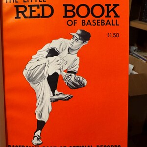 May include: The 1962 Little Red Book of Baseball, a bright orange book with a black and white illustration of a baseball player pitching. The book is titled "Baseball's Book of Official Records" and is the 37th annual edition.