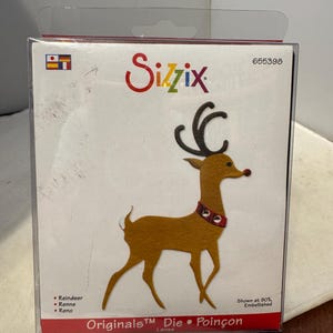 May include: A Sizzix die-cut reindeer craft kit. The reindeer is brown with black antlers and a red collar. The packaging features the Sizzix logo and the words "Originals Die Poinçon". The kit is labeled "Large".