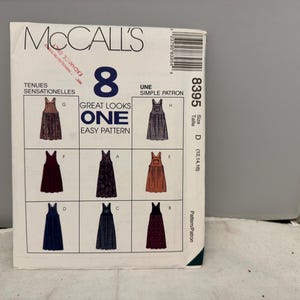 Puede incluir: Patrón de costura McCall's con ocho diseños de vestidos. El patrón incluye el texto "Great Looks One Easy Pattern" y la talla D (12, 14, 16). La portada muestra ilustraciones de los estilos de vestidos en varios colores y patrones.