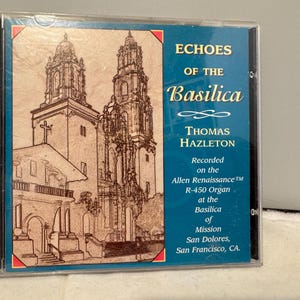 Puede incluir: Una caja de CD con el álbum "Echoes of the Basilica" de Thomas Hazleton. La portada muestra un boceto detallado de una iglesia con dos torres. El texto indica que la grabación se realizó en el órgano Allen Renaissance.