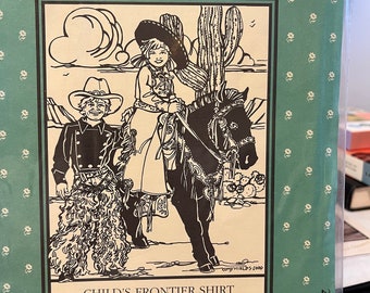 May include: A vintage sewing pattern for a child's frontier shirt. The pattern is illustrated with a child wearing a cowboy hat and a child riding a horse. The pattern number is 218 and the text "Folkwear" is printed on the top of the pattern.