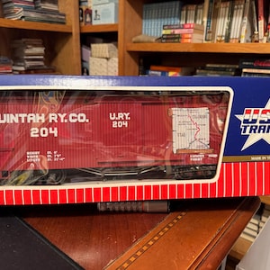 May include: A boxed model train car from USA Trains. The red car has the text "UINTAH RY. CO. 204" and "U.R.Y. 204" printed on it. The box is blue with a white star and the words "USA TRAINS".