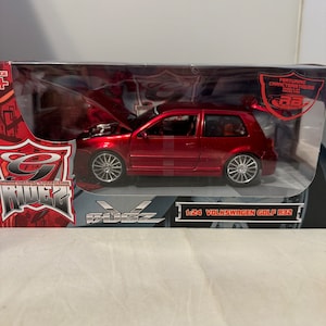 May include: A red 1:24 scale diecast model of a Volkswagen Golf R32 in a clear plastic display case. The car has black wheels and a black interior. The packaging features the words "Urban Diecast Collection" and "Ridez".