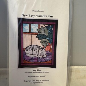 May include: Sew Easy Stained Glass pattern for a cat napping in a window. The design area is 20 1/2 inches by 26 1/2 inches. The pattern includes an optional spotted cat pattern. Copyright 1998 Amy D. Helmkamp. All rights reserved.
