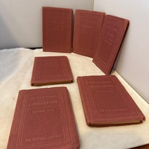 May include: Six small antique books with red covers. The titles are embossed in a lighter shade of red. The books are arranged on a white surface. The books are from The Nutshell Library.