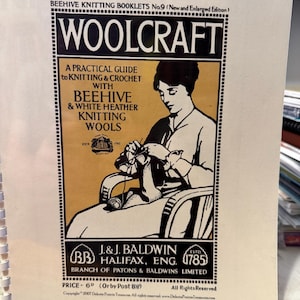 Könnte beinhalten: Ein Vintage-Buchumschlag für einen Strickleitfaden mit dem Titel "Woolcraft: A Practical Guide to Knitting & Crochet with Beehive & White Heather Knitting Wools". Das Cover zeigt eine Frau, die in einem Stuhl sitzt und strickt, mit einem Wollknäuel auf ihrem Schoß. Das Buch wurde von J. & J. Baldwin, Halifax, England, herausgegeben, gegründet im Jahr 1785.