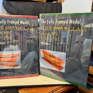 May include: Two books titled "The Fully Framed Model, HMN Swan Class Sloops 1767-1780" Volume I and II. Each book features a detailed illustration of a wooden ship model. The covers are dark with gold lettering and a red and green border.