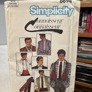 Può includere: Una busta vintage per modelli di cucito Simplicity Connoisseur Collection. La busta è bianco sporco con testo blu e illustrazioni di abiti e cravatte da uomo. Il numero 6694 è stampato in alto.