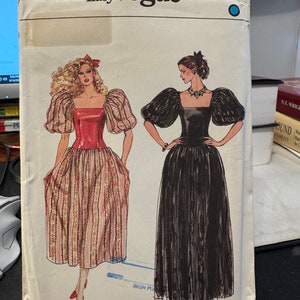 Puede incluir: Un patrón de costura vintage para un vestido con mangas abullonadas. El patrón es para la talla 10 y es de la línea Very Easy Vogue. El patrón muestra dos estilos diferentes del vestido, uno con un corpiño rojo y una falda a rayas y el otro con un corpiño negro y una falda negra.