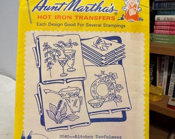 May include: A vintage Aunt Martha's Hot Iron Transfers package in yellow. The cover displays blue and white illustrations of kitchen designs, such as glasses, a teapot, and a plate. Text includes "Kitchen Usefulness" and "For Embroidery, Textile Painting."